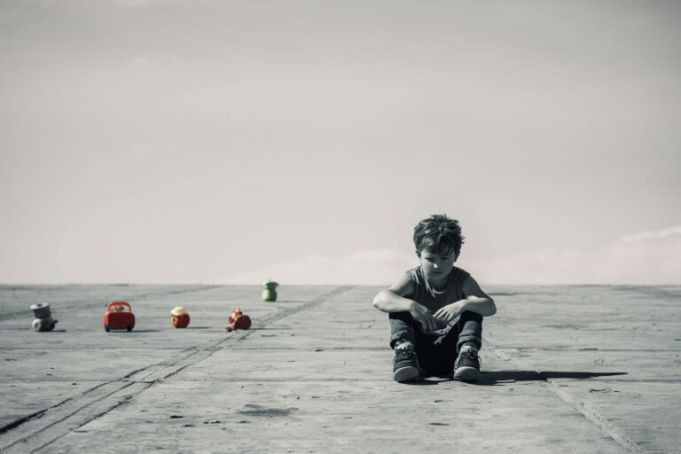 Un niño sentado en el piso de un páramo desolado, no pudiendo jugar.