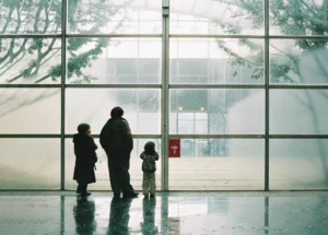 Unos niños mirando a través de un ventanal gigante de una institución gigante